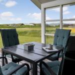 Terrasse mit Tisch und Stühlen, Blick auf grünes Feld und Häuser.