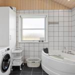 Badezimmer mit Badewanne, Waschmaschine und Fenster