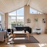 Wohnzimmer mit Holzwänden, großem Fenster und schwarzen Sofas.