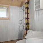 Badezimmer mit Dusche, Waschbecken und Fenster.