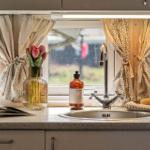 Küchenfenster mit Vorhängen, Blumen, Spüle und Seife