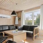 Wohnzimmer mit Holzwand, Sofa, Couch und Fernseher. Große Fenster mit Blick nach draußen.