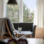 Ein Raum mit einem Sofa, Tisch und Fenster. Vor dem Fenster sind Bäume sichtbar.