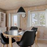 Esszimmer mit runden Tisch, schwarzen Stühlen und Holzwänden. Fenster mit weißen Vorhängen.