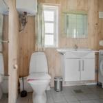 Badezimmer mit Toilette, Waschbecken und Waschmaschine. Holzwand und Fenster.