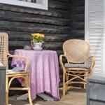 Terrasse mit Tisch, zwei Stühlen und Blumen. Schwarze Holzwand und Holzdielen.