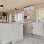 Küche mit weißen Schränken, Holzwand und -decke, Spüle, Mikrowelle und Waschmaschine.