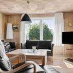 Wohnzimmer mit Holzwand, Sofa, Fernseher und Tisch.