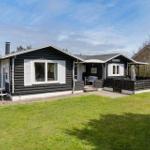 Schwarze Holzhütte mit weißem Fensterrahmen und Terrasse. Grasfläche und Picknicktisch vorne.