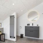 Moderne Badezimmer mit runden Spiegel, grauem Waschtisch und Fenster.