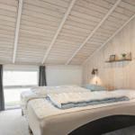 Zwei Betten in einem Raum mit Holzwand und -decke. Fenster mit grauen Vorhängen.