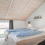 Schlafzimmer mit Bett, Fenster und Holzdecke.