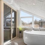 Bad mit freistehender Badewanne und Sauna im Hintergrund.