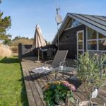 Terrasse mit Liege, Tisch und Sonnenschirm neben einem Holzhaus mit Satellitenantenne.