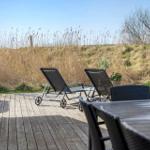 Terrasse mit Liegestühlen und Tisch. Blick auf trockenes Gras und Bäume.