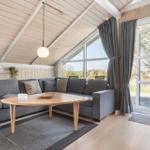 Wohnzimmer mit Sofa, Tisch und großem Fenster. Holzdecke und Boden.
