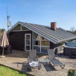 Haus mit Terrasse, Liegen, Whirlpool und Grillplatz im Freien.