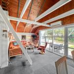 Living room with wooden ceiling, sofa, armchair, and large window to terrace.
