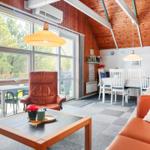 Living and dining area with wooden ceiling, windows, and brown seating.
