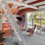 Living room with wooden ceiling, staircase, and large window to terrace.