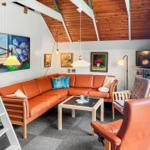Living room with orange sofa, wooden ceiling, and wall paintings.