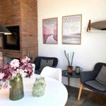 Dining area with table, chairs, and flowers. Wall art and armchairs in the background.