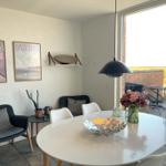 Dining room with round table, chairs, and view of balcony with garden.