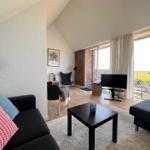 Living room with sofa, coffee table, and TV. Large windows with balcony view.