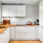 Küche mit weißen Schränken, Holzoberflächen und integriertem Backofen.