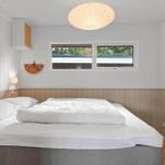 Ein Schlafzimmer mit weißem Bett, Holzwandverkleidung und Fenster.