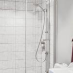 Dusche mit Duschbrause und Handbrause, weiße Fliesen, Handtuch an Haken
