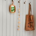 Wand mit Haken, Spiegel, Muschelkette und Tasche mit Obstmotiven.
