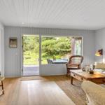 Wohnzimmer mit Holzboden, Sofa, Couchtisch und Blick auf den Garten.