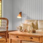 Ein Wohnzimmer mit Sofa, Wickerstuhl und Holztisch. An der Wand hängt eine Lampe.