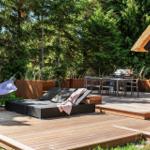 Holzterrasse mit Liege, Hängematte und Grillplatz im Wald.