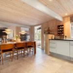 Küche und Essbereich mit Holzdecke, weißen Schränken und Holztisch mit Stühlen.