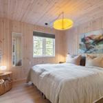 Schlafzimmer mit Holzwand, Bett, Fenster und Deckenleuchte.
