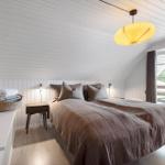 Schlafzimmer mit Bett, Nachttisch und Fenster. Decke und Wände sind weiß verkleidet.