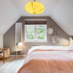 Schlafzimmer mit Dachschrägen, Bett, Fenster und Lampe.