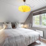 Schlafzimmer mit Dachschrägen, großem Bett und Fenster mit Blick auf Bäume.