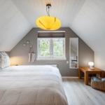 Schlafzimmer mit Dachschrägen, Bett, Fenster und Nachttisch.