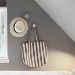 Schlafzimmer mit Dachschrägen, Fenster, Hut und Tasche an der Wand.