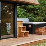 Terrasse mit Whirlpool, Holzbank und Glasfront zur Unterkunft.