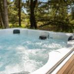 Ein Whirlpool mit blauem Wasser steht auf einer Holterrasse im Wald.
