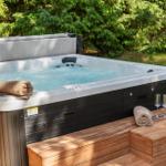 Hochwertige Whirlpool mit Holzterrasse und Getränke im Wald.