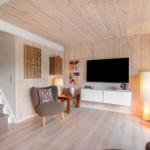 Wohnzimmer mit Holzwand, TV, Sessel und Treppe