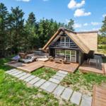 Haus mit strohgedecktem Dach und großem Holzterrasse im Wald