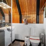Badezimmer mit Dusche, Waschbecken und Toilette unter Holzdecke.