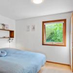 Schlafzimmer mit Bett, Fenster und Holzmöbeln.