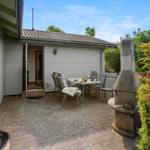 Terrasse mit Tisch, Stühlen und Grill. Hinterhof mit Beerensträuchern und Bäumen.